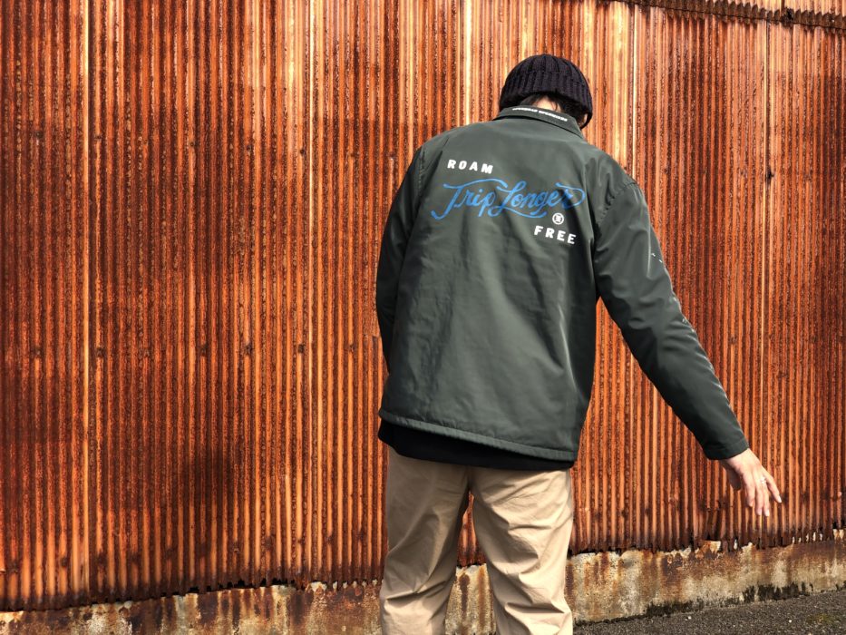 ROARK REVIVAL（ロアークリバイバル）の新作のカーキ色のジャケットに袖を通している男性